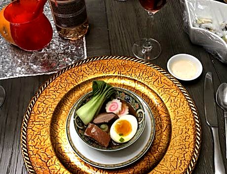 A bowl of kamo ramen with duck, a halved soft egg, bok choy, and narutomaki.